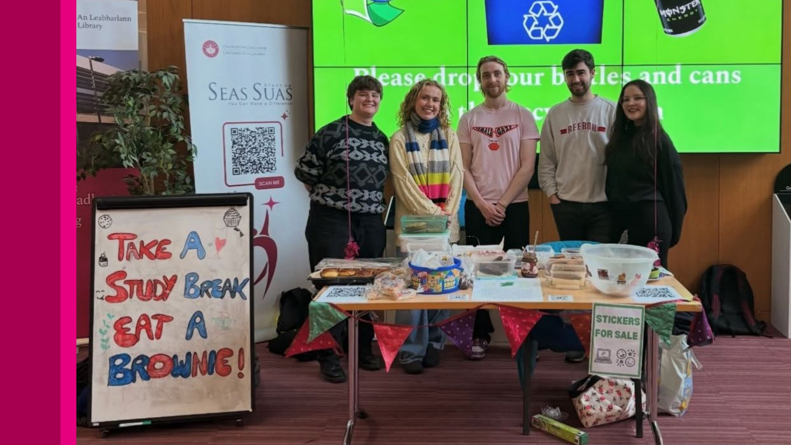 Four students standing at a bake sale stall.