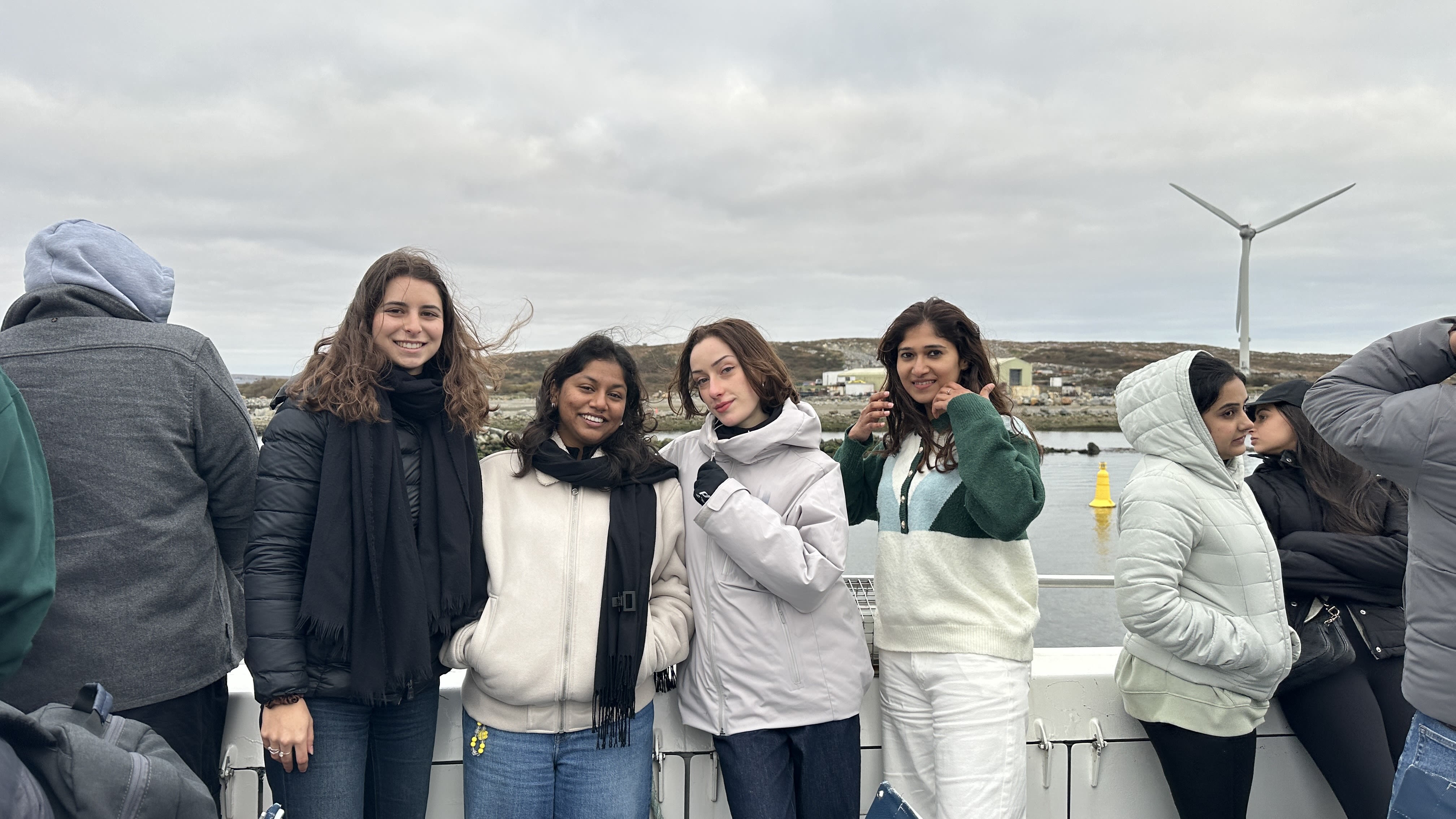 Four friends wrapped up in jackets and scarves on a boat.